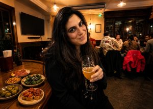 Γυναίκα απολαμβάνει μπύρα και τάπας σε μπαρ στην Ισπανία, γνωρίζοντας την τοπική γαστρονομία και τον ισπανικό τρόπο ζωής. Λεζάντα (Λεζάντα) Μια μπύρα, λίγα τάπα και η καθημερινότητα στην Ισπανία όπως τη ζουν οι ντόπιοι.